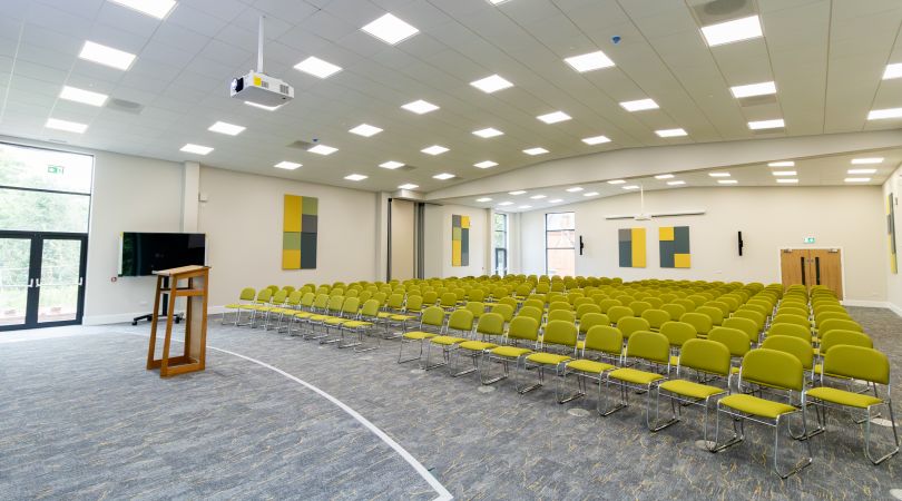 Large conference hall with stage and rows of chairs