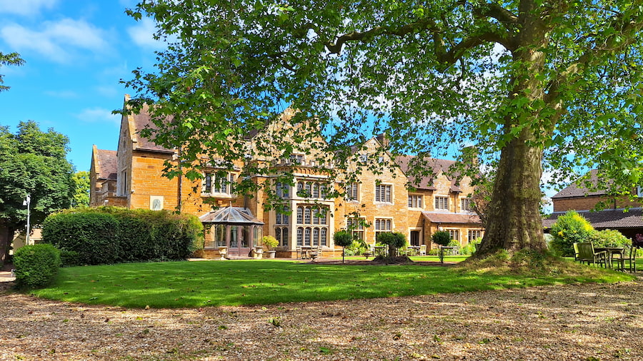 Highgate House in the sun with the large tree in front.