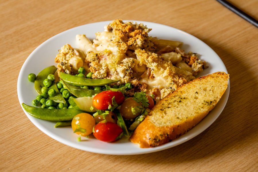 A plate of food at Highgate House with pasta, garlic bread, and vegetables.