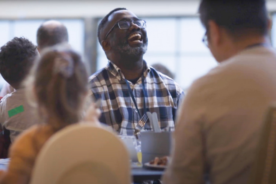 A man laughing during lunch with his church family.