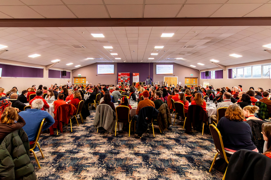 A wide angle shot of Christian Aid having a session in the Derbyshire Hall set out in cabaret style