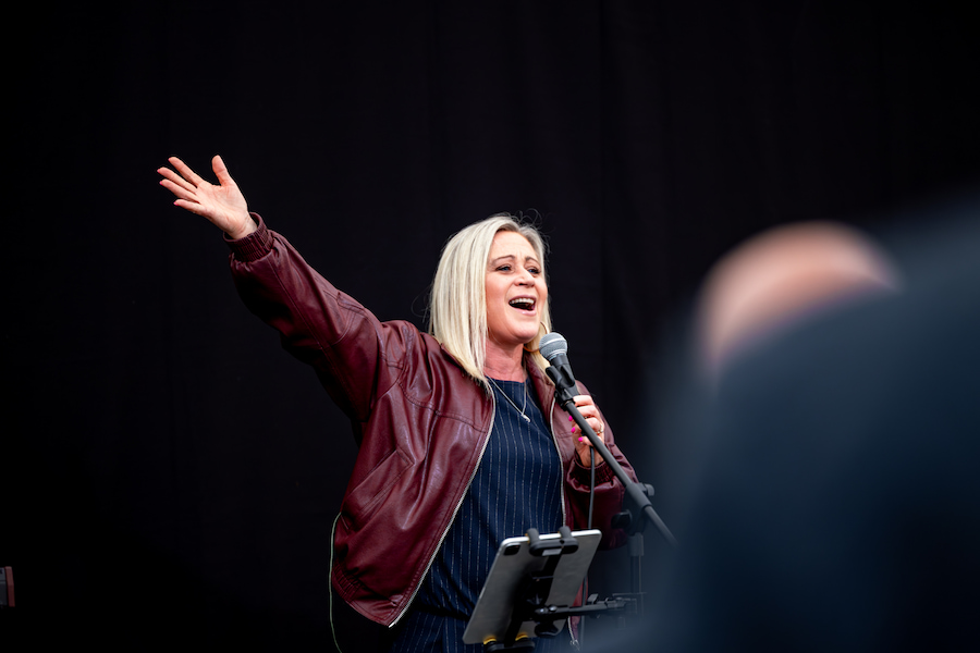 Lou Fellingham signing into the mic with her hand up.