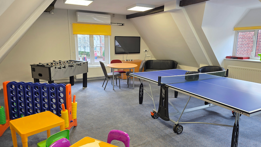 The other side of the Play Room showing the football table, more toys, and a screen with 2 Playstation 5 controllers.