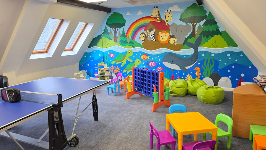 The Play Room showing the colourful Noah's Ark mural, kids toys, and the ping pong table.