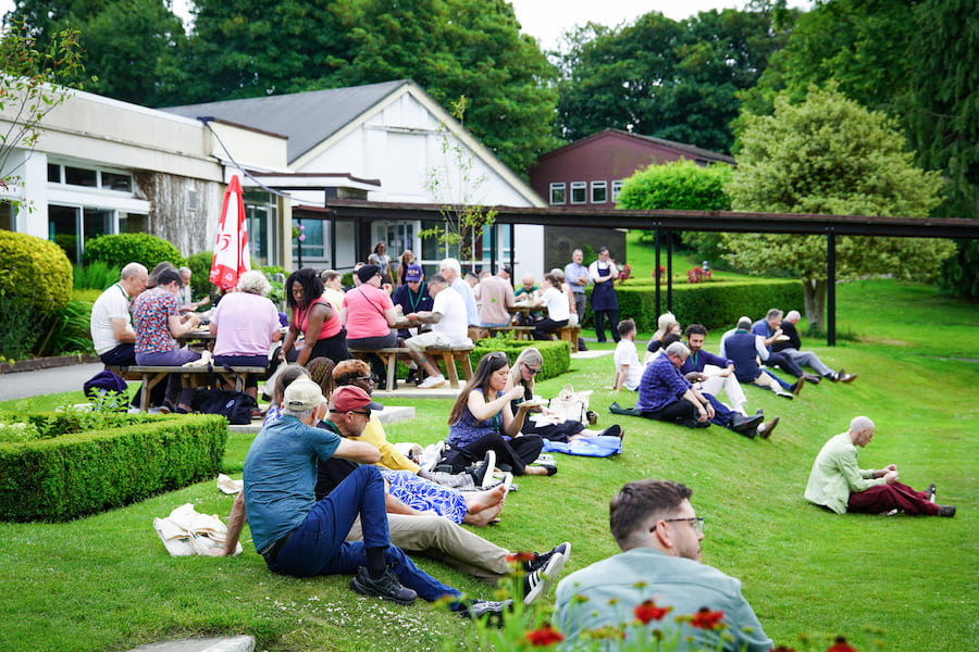 People sitting on the lawn eating and chatting together at The Hayes.