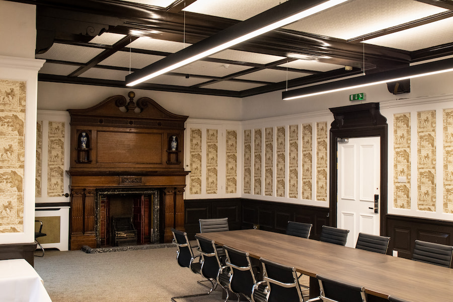 The Boardroom today with a large boardroom table and chairs with the original fireplace still there.