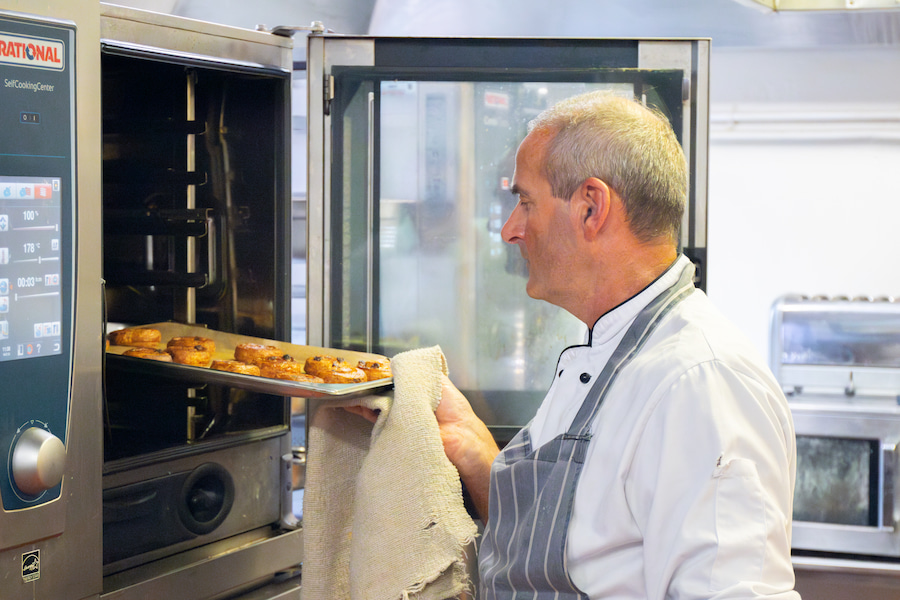 A cook taking some pastries out of the new oven.