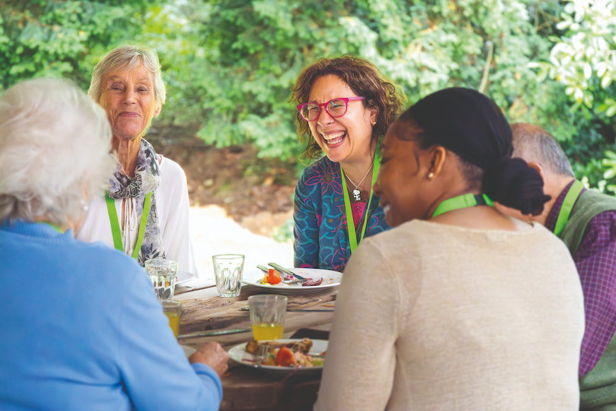 A group of people laughing while having lunch together.