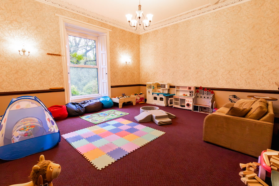 The soft play area with a sofa, toys and a soft mat.