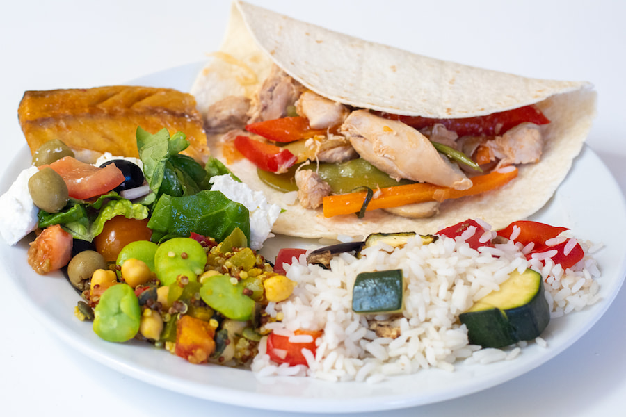 A colourful plate of food including fajitas, vegetable rice and a delicious salad.