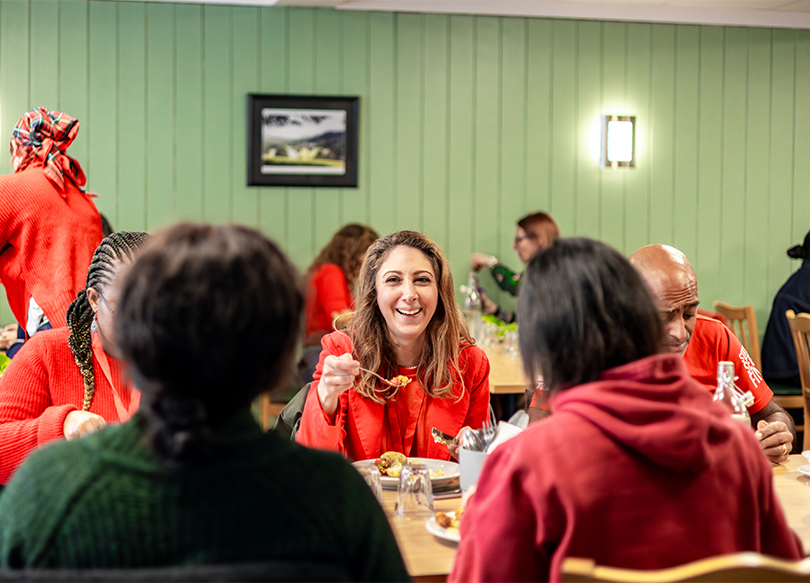 A woman sitting with her friends at a dining room table at The Hayes laughing together over a meal.